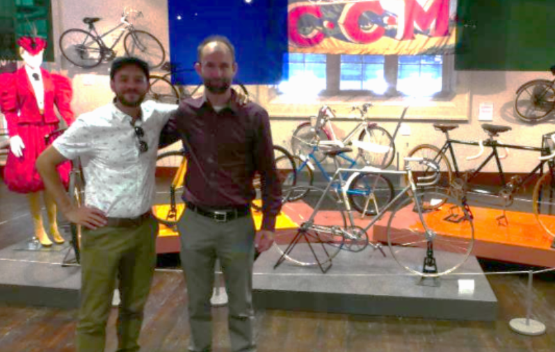 Friends standing proudly in front of bicycle display.